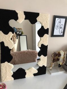 a cow print mirror sitting on top of a white table next to a black and white chair