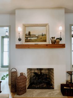 a living room with a fire place next to a painting on the wall and two wicker baskets