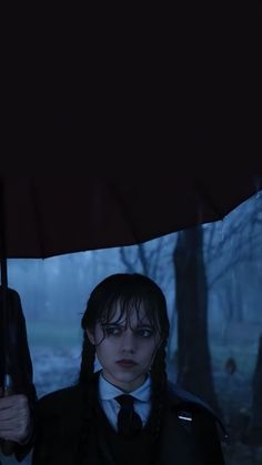 two people standing under an umbrella in the dark, with one person wearing a suit and tie