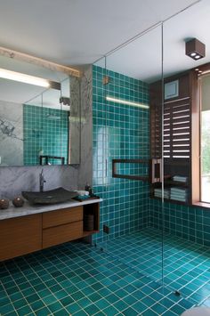 a bathroom with blue tiles on the floor and walls, along with a walk in shower