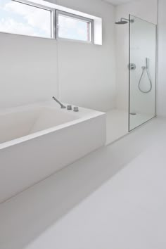 a white bathroom with a large bathtub next to a window and a shower head