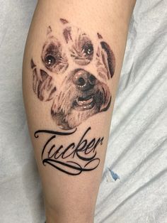 a close up of a person's leg with a dog on it and the word tucker written in cursive ink