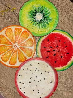 four slices of fruit are arranged on a table top, including oranges and watermelon