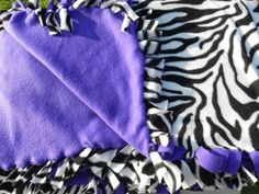 two purple and black towels laying on top of each other in the grass with zebra print