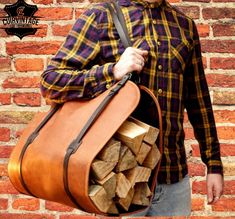 a man is holding a bag full of firewood in front of a brick wall