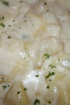 a close up view of some food in a white sauce with green garnish