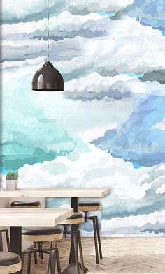 a dining room table with chairs and a painting on the wall behind it that has clouds in the sky