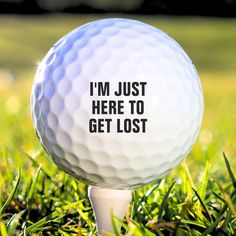 a golf ball with the words i'm just here to get lost on it