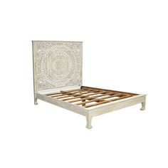 a white bed with wooden slats and an intricate design on the headboard is shown