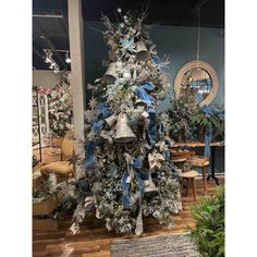 a decorated christmas tree with blue and silver ribbons on it in a room filled with furniture