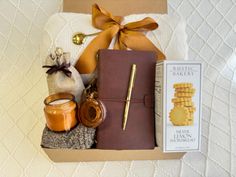 a gift box with honey, cookies and other items in it sitting on a bed