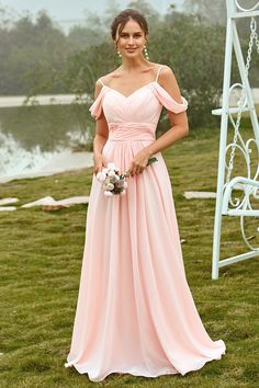 a woman in a long pink dress posing for the camera with her bouquet and flowers