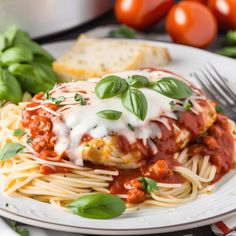 a white plate topped with pasta covered in sauce and cheese next to sliced bread on a table