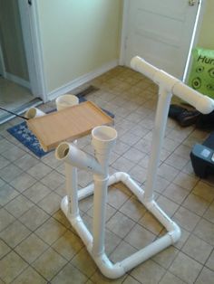 a white pipe and wooden table in a room with tile flooring on the ground