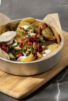 a metal pan filled with food on top of a wooden cutting board