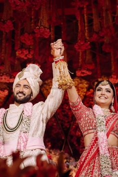 the bride and groom are holding their hands in the air