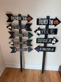 several black and white wooden signs pointing in different directions on a wood floor next to a wall