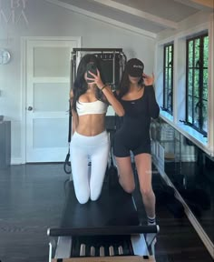 two women in black and white outfits standing on a treadmill