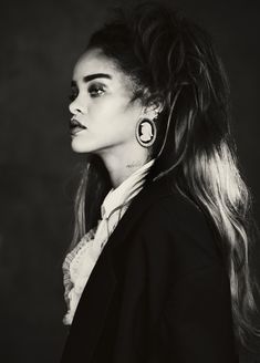 a black and white photo of a woman with long hair wearing large earrings