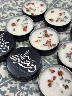 several small black tins filled with different types of flowers on a patterned table cloth