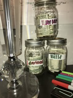 jars filled with money sitting on top of a table next to markers and pens,