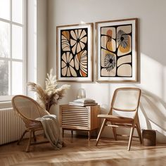 two framed art work on the wall next to a chair and side table in front of a window