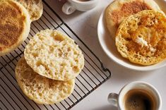 some food is on a cooling rack next to two cups of coffee and saucers