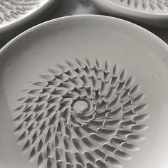 several white plates with designs on them sitting on a counter top in black and white