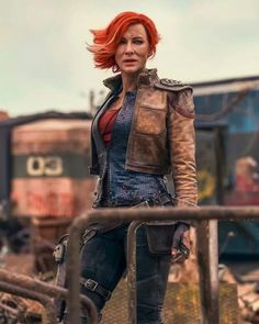 a woman with red hair and leather jacket standing in front of a train track, looking at the camera