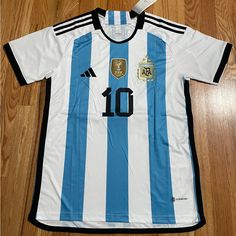 a soccer jersey with the number 10 on it sitting on a wooden floor next to a pair of scissors