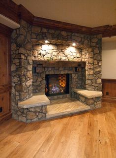 a stone fireplace with two benches in front of it and the fire place is lit