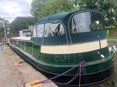 a green and white boat tied to the dock