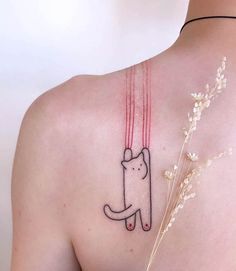 a woman with a cat tattoo on her back and shoulder, holding the string attached to it