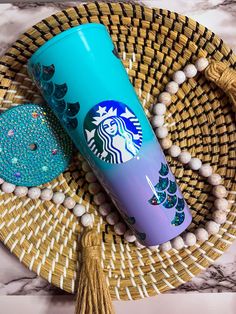 a starbucks cup sitting on top of a wicker tray next to a tassel