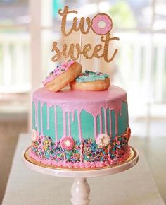 two sweet donuts on top of a pink and blue cake with sprinkles