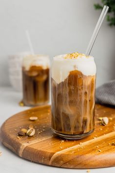 two glasses filled with iced coffee on top of a wooden cutting board