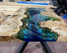 a table that is made out of wood and has blue paint on the top, along with black metal legs