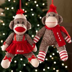 two stuffed monkeys hanging from strings in front of a christmas tree