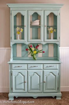 a blue china cabinet with flowers in it