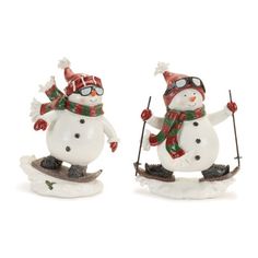 two snowmen on skis wearing hats and scarves, one holding ski poles