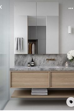 a bathroom vanity with marble counter top and wooden cabinetry, along with white flowers