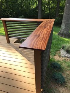 a wooden bench sitting on top of a wooden deck next to a tree filled forest