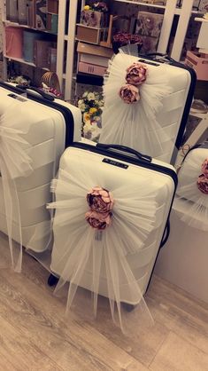 three pieces of luggage covered in white tulle and pink flowers with bows on them