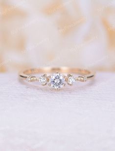 an engagement ring with three stones on it, sitting on top of a white cloth