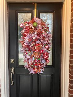 a christmas wreath on the front door of a house decorated with candy canes and candies