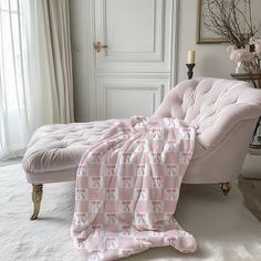 a bed with a pink blanket sitting on top of it next to a white couch