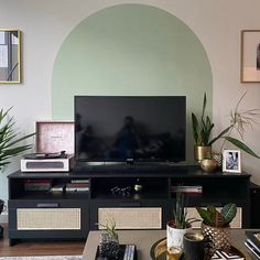 a flat screen tv sitting on top of a black entertainment center in a living room