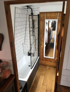 an open door leading to a bathroom with a bathtub and mirror on the wall