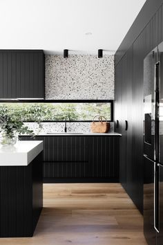 a modern kitchen with black cabinets and white counter tops, along with an island in the middle