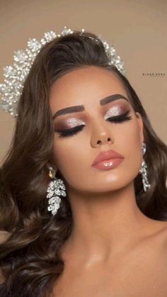 a woman with long brown hair wearing a tiara and makeup looks into the distance